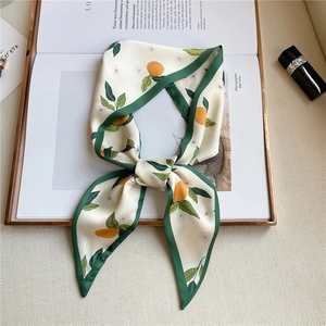 Detail of silk-like neckerchief with orange fruit print and green contrast borders