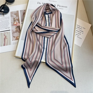 Artistic layout of champagne gold striped twilly silk scarf on a magazine background