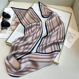 Detail of a thin silk-like striped scarf displayed with stylish lifestyle accessories