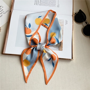 French style silk scarf with orange fruit print tied in a bow on a lifestyle magazine