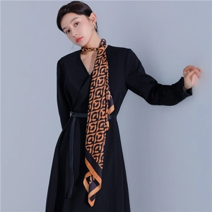 Detail of elegant orange and black geometric pattern silk scarf draped on neck