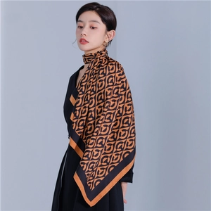 Detail of the high-quality silk scarf showing black and orange geometric patterns and drape