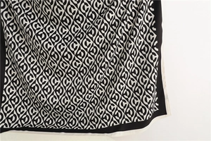 Macro shot of silk scarf fabric featuring black and white geometric letter C pattern