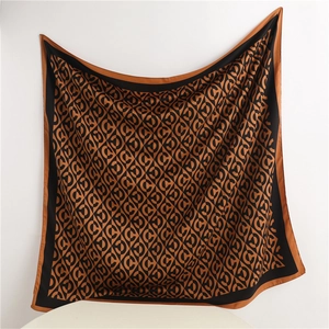 Detail of caramel silk square scarf featuring black border and luxury monogram pattern