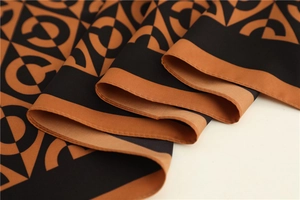 Detailed close-up of geometric pattern silk scarf with caramel and black contrast colors