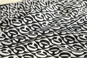 Detailed close-up of the black and white silk scarf showing fine twill weave and C-pattern