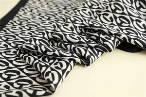 Detailed view of luxury silk scarf texture with black and white geometric letter pattern