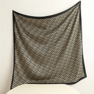 Detail view of large silk scarf featuring elegant black and beige monogram pattern