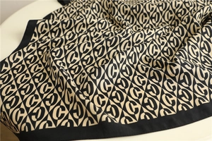 Macro shot of silk square scarf featuring black and beige geometric C-letter patterns