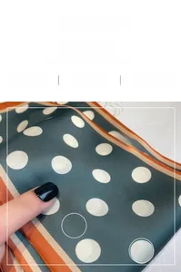 Detail showing high-quality dark green polka dot silk scarf with striped hem texture