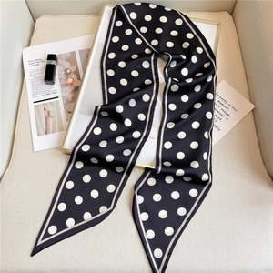 Close-up of a long polka dot silk scarf with contrast borders and chic prop styling