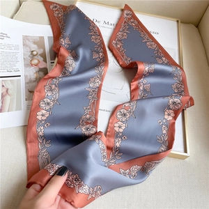 Close-up of floral print satin twilly scarf with blue and terracotta borders over art books