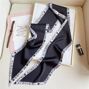 Detail of silk-like satin twilly scarf with black rose print and elegant lettering