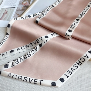 Detail of pink satin scarf with rose patterns and lettered contrast borders on a magazine