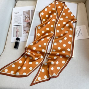 Close-up of orange polka dot twilly scarf in a tray with lifestyle magazines