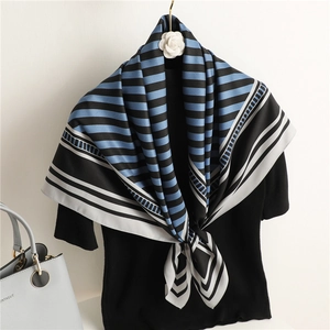 Detail of blue and black striped twill silk scarf draped with a white flower brooch