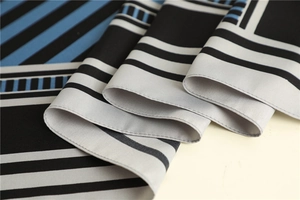 Detailed view of silk scarf fabric showing high-quality twill texture and geometric stripes