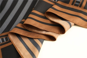 Detail of geometric stripe silk scarf with fine rolled edges and smooth texture