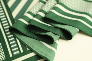 Detail of green and white geometric striped silk scarf showing soft texture and fine edges