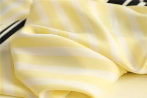 Macro detail of yellow and white striped silk scarf showing fine twill texture and soft sheen