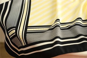 Detailed close-up of striped silk scarf texture and geometric patterns in cream and black