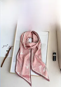 Détail d'un foulard Twilly rose avec montre et rouge à lèvres sur cadre blanc