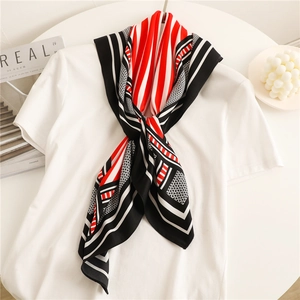 Detail of red and black striped silk scarf styled on a white shirt with a modern geometric pattern