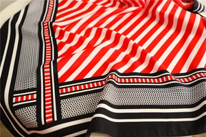 Detailed view of striped twill silk scarf with red and black geometric pattern design