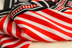 Detail of red and black striped twill silk scarf with smooth texture and soft luster