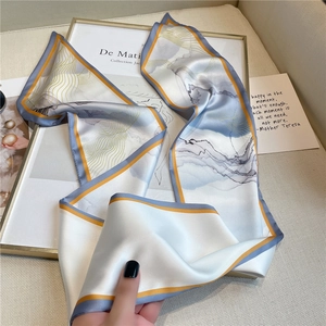 Détail macro du foulard en soie synthétique à motifs bleus et bordure dorée chic