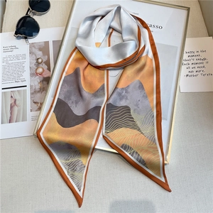 Détail d'une écharpe en soie chic avec motifs de montagne et bordure orange raffinée