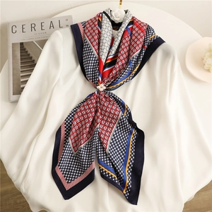 Detailed view of houndstooth silk scarf with pearl brooch on white shirt