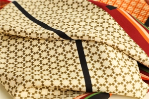 Macro detail of houndstooth silk scarf showing smooth texture and colorful geometric patterns