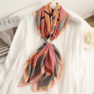 Detail of houndstooth silk scarf with pearl floral clip on white linen shirt