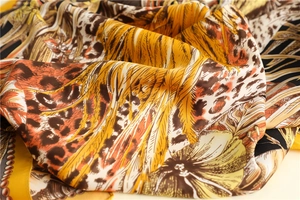 Detailed macro view of leopard print and palm leaf silk scarf with golden satin finish