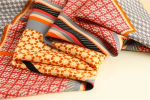 Detailed close-up of houndstooth silk scarf featuring orange and burgundy geometric patterns