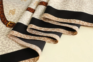 Detail of silk-texture scarf showing brown belt patterns and black border trim