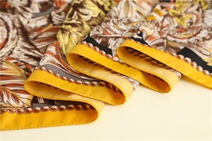 Detailed macro shot of yellow silk scarf with baroque floral prints and twill texture