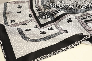 Detailed close-up of fish scale pattern twill silk scarf with buckle and logo prints