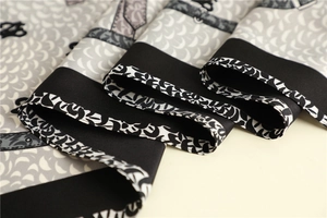 Close-up of fish scale pattern silk scarf with fine rolled hem and abstract prints