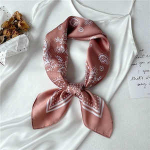 Close-up of pink paisley silk scarf styled as a bow on a white satin dress
