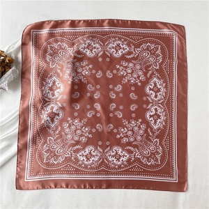 Detail of terracotta silk-like square scarf featuring classic white paisley patterns