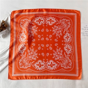Close-up of bright orange paisley silk scarf with vintage geometric patterns on a white background