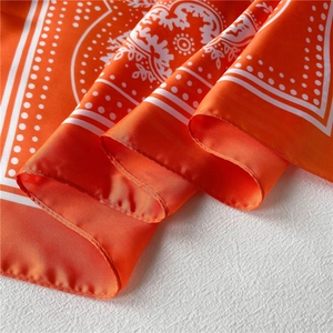 Detailed view of orange paisley silk scarf texture with soft drapes and satin finish