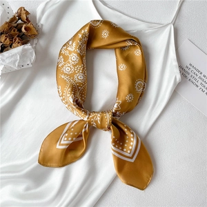 Golden silk square scarf with paisley pattern on a white dress with dried flowers
