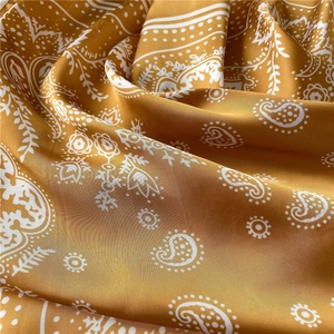 Close-up of yellow paisley print silk satin fabric showing detailed fold texture