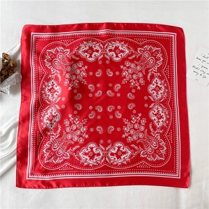 Detail of red paisley silk-like scarf with floral patterns on white textured fabric