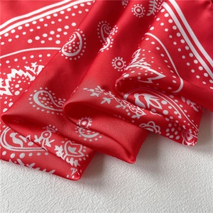 Close-up of red paisley silk scarf with glossy texture and elegant draped fabric folds