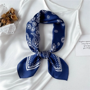 Navy blue silk-like paisley square scarf styled on a white top with dried flowers