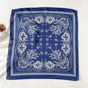 Close-up of a navy blue square silk-like scarf featuring intricate white paisley patterns